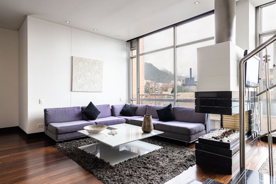 Bright and stylish modern living room with large windows, a cozy couch, and a city view.